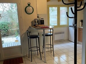 A kitchen with a window, a clock, and two stools. - House with air conditioning - 6 guests (Moliets-et-Maa)