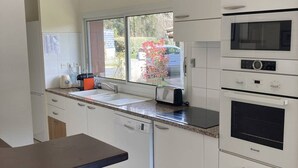 Une cuisine avec une fenêtre, un grille-pain, un évier et un four à micro-ondes.