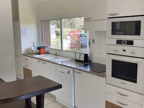 A kitchen with a window, a toaster, a sink, and a microwave. - Family villa with heated pool - 6 guests (Moliets-et-Maa)
