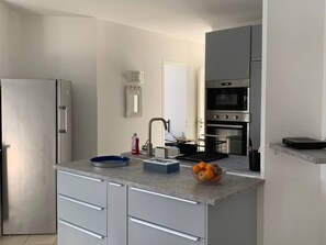 Eine moderne Küche mit Kühlschrank, Backofen und Spüle mit Wasserhahn.