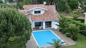 Une maison avec une piscine, entourée de verdure et dotée d’une antenne parabolique.