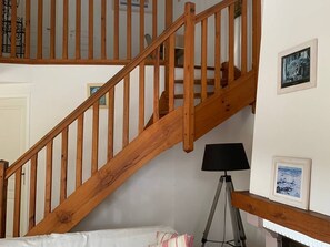 Eine Holztreppe in einem Raum mit einem Bett, einer Lampe und gerahmten Bildern an der Wand.