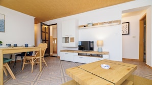 A modern kitchen with a dining area, a TV, and a wooden table. - Family-friendly accommodation with terrace & garden (Tribalj)