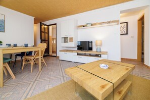 Eine moderne Küche mit Essbereich, einem Fernseher und einem Holztisch.