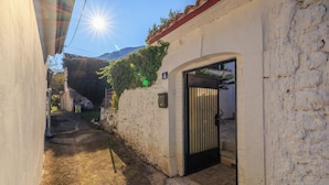 A narrow alleyway with a white building, a black gate, and a mountain in the background. - Family-friendly accommodation with terrace & garden (Tribalj)