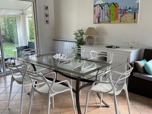 A dining area with a glass table and white chairs, a white cabinet with a lamp, and a painting on the wall. - House with heated pool - 8 guests (Moliets-et-Maa)