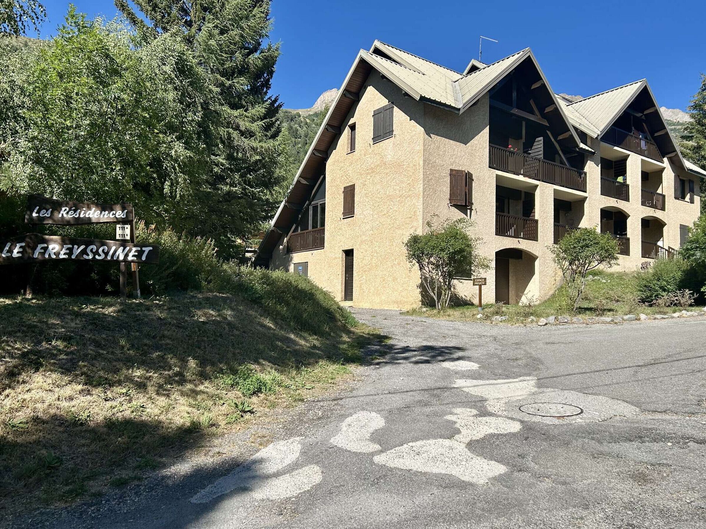 A two-story building with a stone facade, multiple balconies, and a sign indicating 'Les Residences' and 'LE FREYSSINET.'