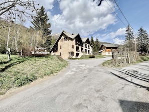 A lodge with a prominent entrance, multiple balconies, and a mountainous backdrop. - Spacious apartment with private garden - 6 guests (Le Monêtier-les-Bains)