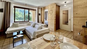 Una stanza con un divano, un tavolo da pranzo per due persone e una parete in legno decorata con un cuore.