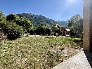 A grassy area with a building and trees, a clear sky, and mountains in the background. - Spacious apartment with private garden - 6 guests (Le Monêtier-les-Bains)