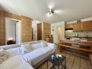 Een knus woongedeelte met een bank, een eettafel en een kitchenette.