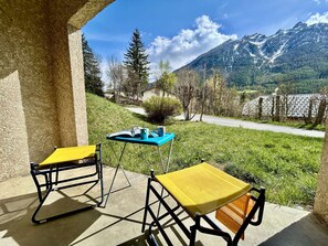 A terrace with two yellow chairs and a table, overlooking a road and mountains. - Spacious apartment with private garden - 6 guests (Le Monêtier-les-Bains)