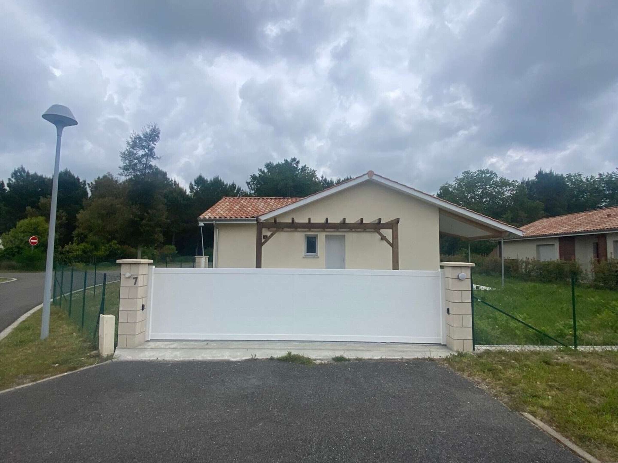 Edificio residenziale con portico coperto, ingresso chiuso da cancello e cartello stradale che indica divieto di accesso.
