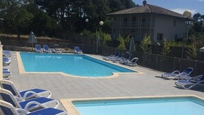 A swimming pool with lounge chairs and a building in the background. - Comfortable apartment with parking - 8/10 guests (Moliets-et-Maa)