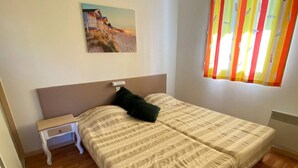 A bedroom with a bed, a nightstand, a painting, and a window with curtains. - Comfortable apartment with parking - 8/10 guests (Moliets-et-Maa)