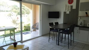 Uma cozinha moderna com área de refeições, uma TV fixada na parede e uma porta de vidro deslizante que dá para um pátio externo.
