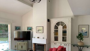 A living room with a TV, fireplace, red sofa, and a glass coffee table. - Villa with pool - 10 guests (Moliets-et-Maa)