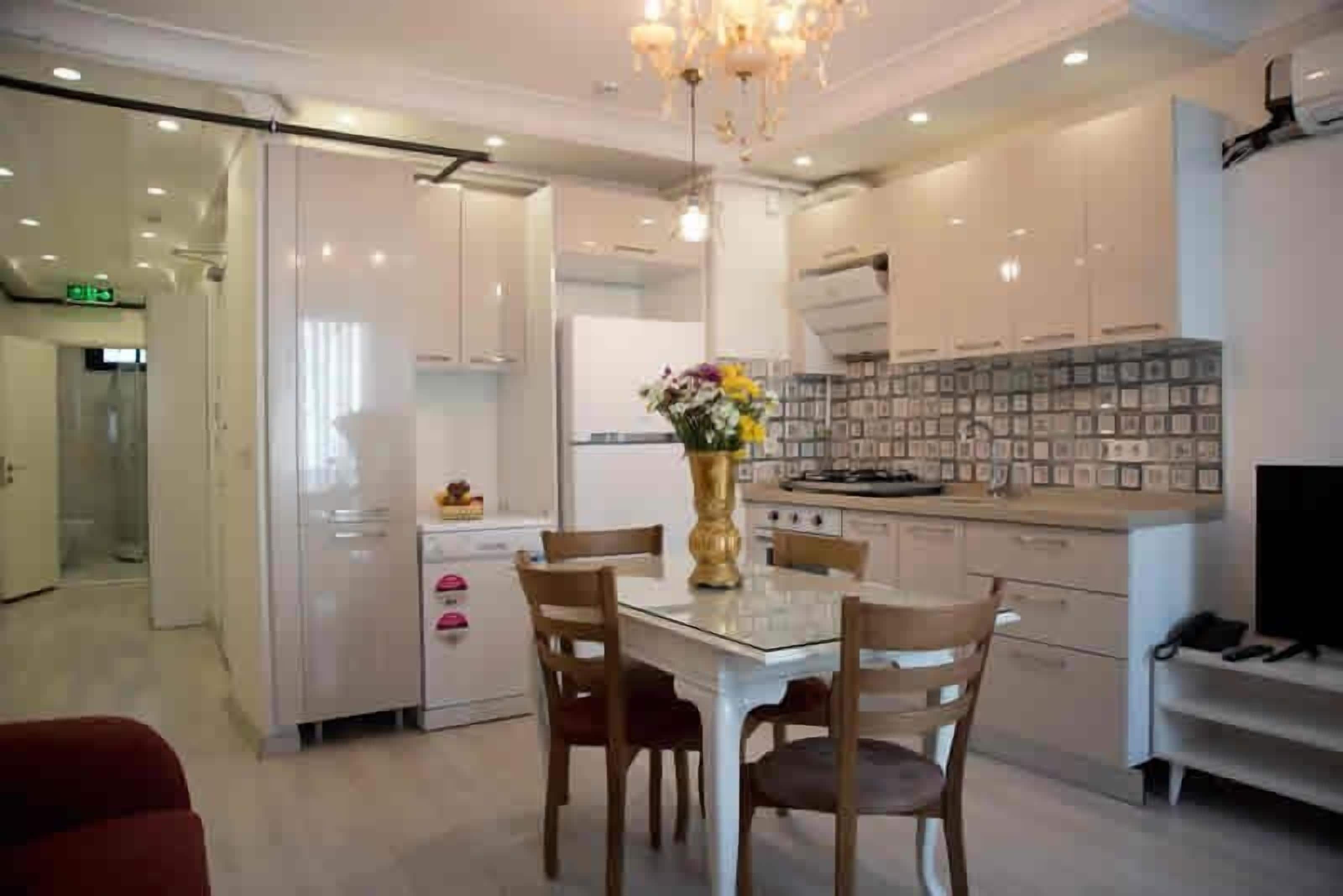 Une cuisine moderne avec une table à manger, des chaises et un vase de fleurs.