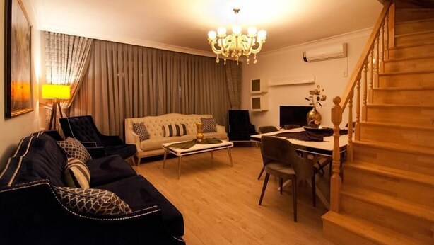A living room with a sofa, coffee table, and a dining table with chairs. - Nupelda Residence (İstanbul)