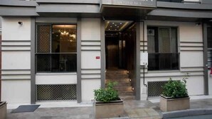 A hotel entrance with a sign reading 'NUPELDA,' a staircase leading inside, and two planters with greenery. - Nupelda Residence (İstanbul)