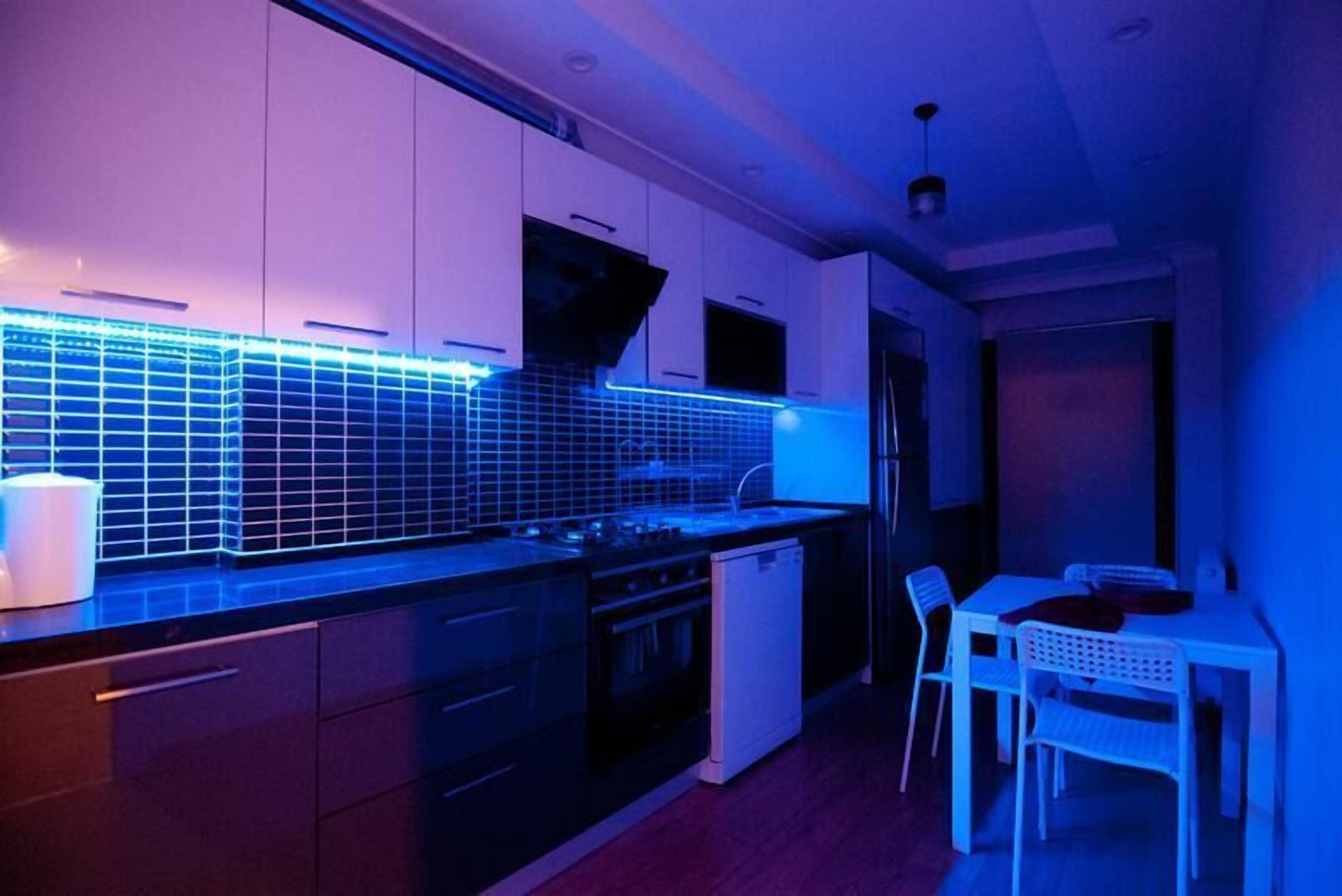 A compact kitchen with modern appliances, a dining area with chairs, and a small refrigerator.