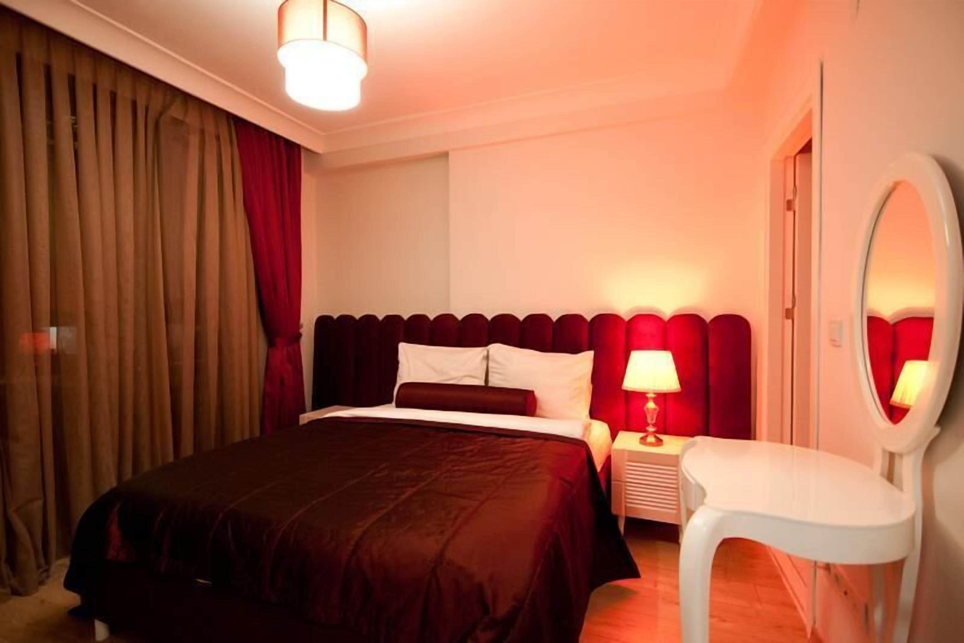 Ein Hotelzimmer mit Bett, Nachttisch, Lampe und Spiegel.
