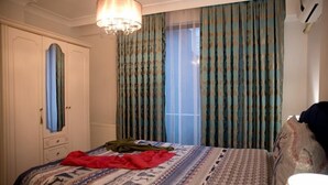 A bedroom with a bed, a wardrobe, a mirror, and a window with curtains. - Nupelda Residence (İstanbul)