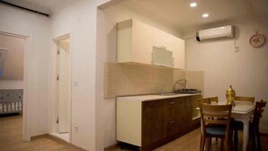 A compact kitchen with a dining area, wooden cabinets, and a small island. - Nupelda Residence (İstanbul)