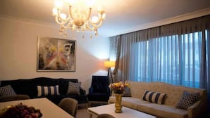 A living room with a sofa, a coffee table, a chandelier, and a painting on the wall. - Nupelda Residence (İstanbul)