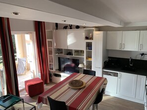 Ein kompakter Wohnbereich mit Essplatz, Küchenzeile und Fernseher.