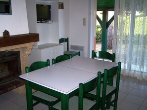 Un comedor con una mesa y sillas, un televisor sobre la mesa, y una chimenea.