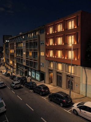 Ein mehrstöckiges Hotel mit beleuchteten Fenstern, einem Parkplatz und Blick auf die Straße.