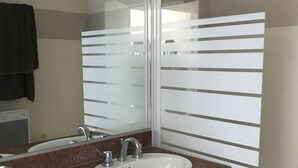 Un baño con dos lavamanos, un espejo y paneles de vidrio esmerilado.