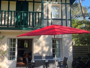 A two-story house with a balcony, a red umbrella, and a bicycle parked outside. - Spacious house with Wifi - 6 guests (Moliets-et-Maa)