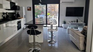 A modern kitchen with a dining area, a sofa, and a TV. - Spacious house 600m from Empúries beaches with private terrace (L'Escala)