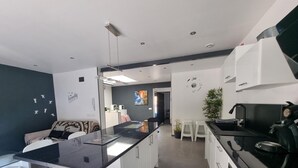 A modern kitchen with a central island, white cabinets, and a black stove. - Spacious house 600m from Empúries beaches with private terrace (L'Escala)