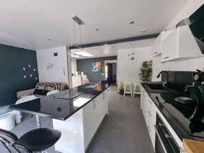 A modern kitchen with a central island, white cabinets, and a black stove. - Spacious house 600m from Empúries beaches with private terrace (L'Escala)
