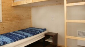 A small, single-bed room with a bunk bed above, wooden walls, a small bedside table, and a power outlet on the wall. - Cozy chalet, pets welcome - 6 guests (Villegly)