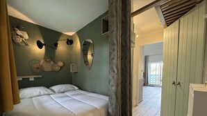 Een slaapkamer met een bed, wandlampen, een spiegel en een kledingkast.
