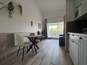 Eine moderne Küche mit Essbereich, Blick ins Freie und Deckenbalken.