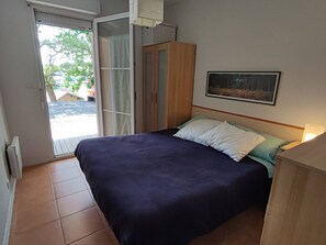 Ein Schlafzimmer mit Bett, Schrank, einer Schiebetür und einem gerahmten Bild an der Wand.