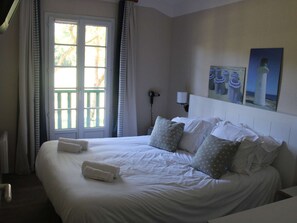 Habitación de hotel con una cama grande, una ventana con cortinas, una lámpara de noche y un cuadro en la pared.