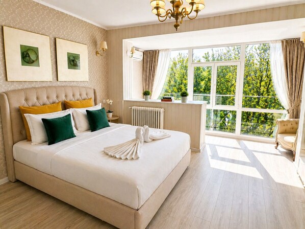 Un dormitorio amplio con una cama grande, vistas a la vegetación por la ventana y una zona de estar acogedora.