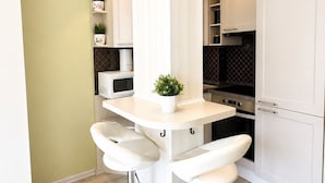 Una cocina moderna con armarios blancos, una isla central con taburetes, un microondas y una estufa.