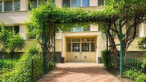 Entrada de un edificio con puerta portón, camino pavimentado y vegetación.