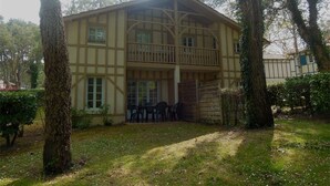 Un bâtiment à deux étages doté d’un balcon, entouré d’arbres.
