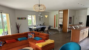 Un salon moderne comprenant un canapé d’angle, un coin repas et une cuisine.