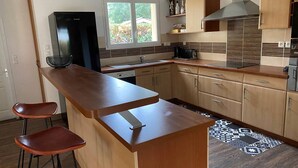 Une cuisine moderne dotée d’un îlot central, de tabourets de bar, d’un réfrigérateur, d’une cuisinière et d’une fenêtre.