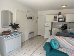 Eine kompakte Küche mit Mikrowelle, Kühlschrank und einer kleinen Essecke mit Tisch und Stühlen.