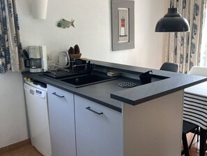 Eine kleine Küche mit Spüle, einer Kaffeemaschine und einer kleinen Fischdekoration an der Wand.